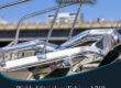 Marmon Keystone Close-up of polished stainless steel tubing on a boat railing with promotional text for Marmon/Keystone welded stainless tube and pipe, A269. In-stock metals, ready to ship from your trusted supply chain distributor. Bridge and sky in the background.