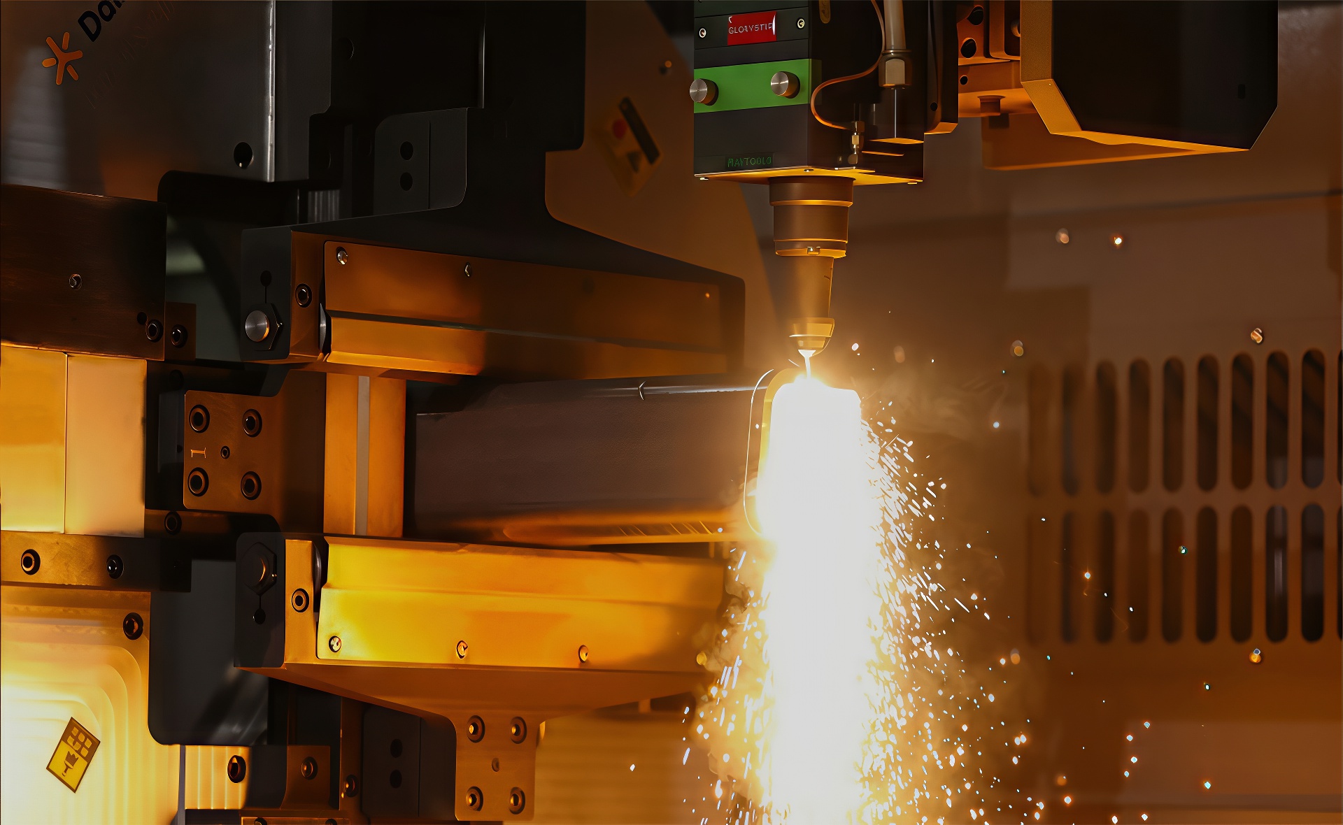 Marmon Keystone A CNC laser cutting machine emits sparks as it cuts through a metal workpiece, with various mechanical components and safety enclosures visible around the cutting area.